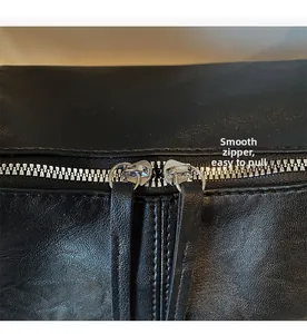 Close-up of smooth dual silver zippers with long leather pullers on a black tote bag