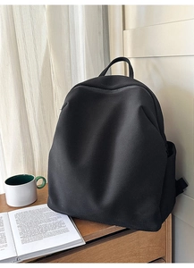 Minimalistischer schwarzer Netzrucksack auf Holzschreibtisch in hellem Raum