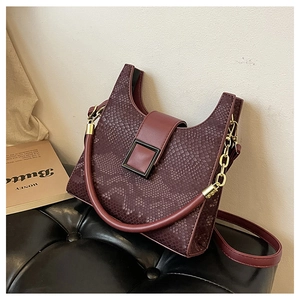 Close-up of wine red embossed snake pattern leather handbag with metallic buckle detail