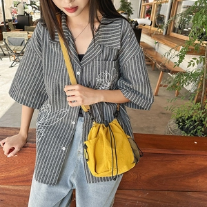 Outdoor shot of a casual yellow nylon bucket bag with adjustable shoulder strap detail