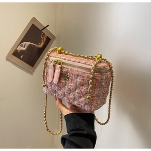 Close-up of pink tweed vanity bag with gold flower clasp and chain strap detail