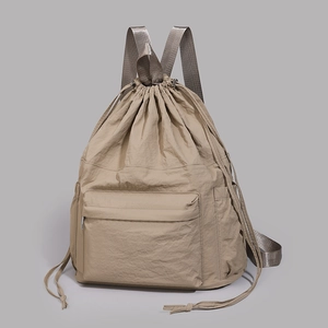 Detailed view of khaki nylon backpack featuring drawstring closure and front zipper pocket