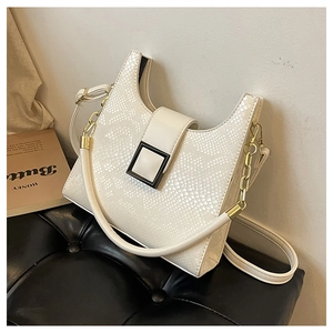 Detail of white snakeskin texture and golden chain strap on a faux leather handbag