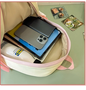 Detail view of pink and yellow backpack showing spacious internal storage for gadgets
