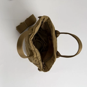 Detail view of khaki quilted crossbody bag showing inner zip pocket and detachable strap