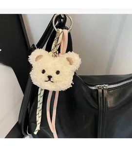 Close-up of a plush bear keychain with woven lanyard on a black vintage tote bag