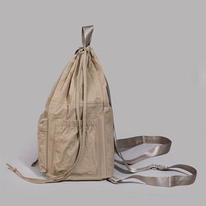Detail view of water-resistant nylon fabric and adjustable metal buckle on beige backpack