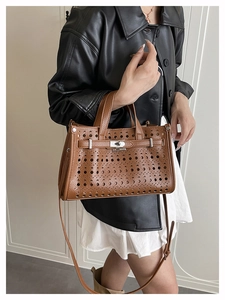 Detail of brown hollow-out tote bag with lychee grain leather and metal twist lock