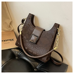 Detail of dark brown faux crocodile texture handbag with gold metal buckle and chain handle