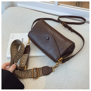 Dettaglio borsa a tracolla marrone vintage con ampia tracolla jacquard e fibbia