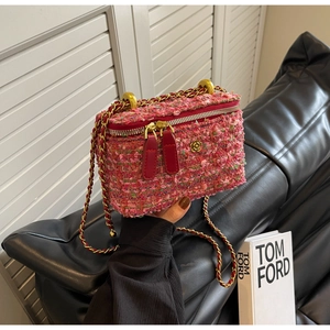 Macro detail of red tweed crossbody bag with gold camellia and chain strap