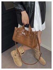 Detail view of brown leather handbag with laser-cut hollow design and metal turn-lock