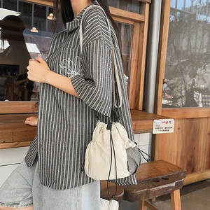 Detail of off-white nylon drawstring bucket bag with mesh pocket on casual outfit