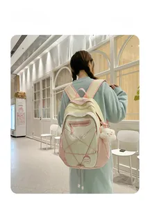 Detail view of pink and white multi-color拼接 backpack with cute plush charm accessory