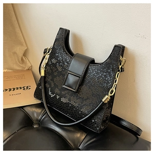 Detail of black faux python texture handbag featuring a square clasp and gold chain handle