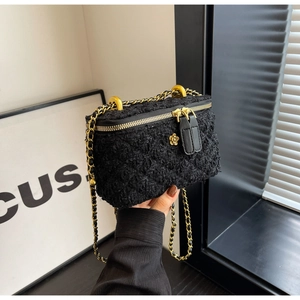 Close-up of black tweed mini bag featuring gold chain strap and floral accent