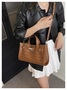 Detailed close-up of brown laser-cut hollow leather handbag with metal turn-lock buckle