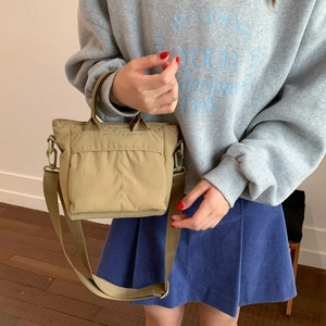 Khaki nylon crossbody bag shown worn by a model in a cozy, minimalist home setting