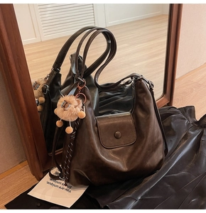Close-up of brown faux leather tote bag with magnetic flap and cute lion plush charm