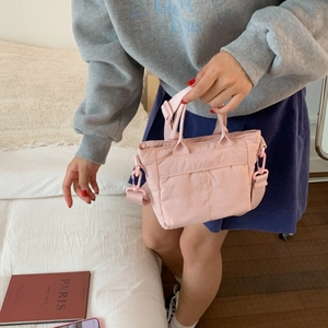 Detail of pink quilted crossbody bag with adjustable strap in a lifestyle bedroom setting