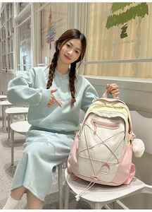 Detail of multi-color canvas backpack with cute plush ball pendant and elastic cord