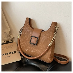 Close-up of brown crocodile embossed faux leather bag with stylish U-shape and metal buckle