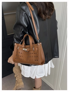 Detail of a brown hollowed-out leather handbag with metal buckle and adjustable strap