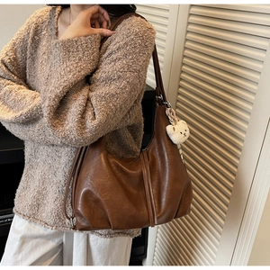 Detail of a large brown faux leather hobo tote with a cute white plush bear charm