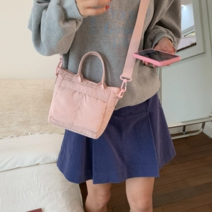 Detail view of pink nylon crossbody bag with dual front pockets on female model