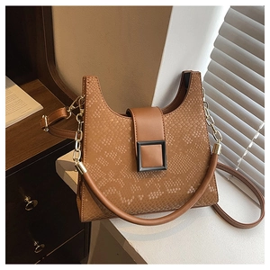 Detailed view of brown snake-embossed leather handbag with square buckle in soft light