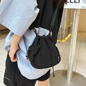 Detail of a black nylon bucket bag with mesh side pocket and a white FASHION woven label