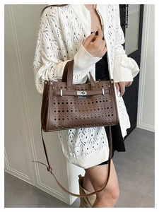 Close-up of brown cutout tote bag featuring silver metal lock and adjustable shoulder strap