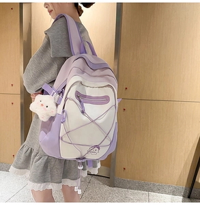 Detail of purple and white school backpack with crisscross cords and plush charm