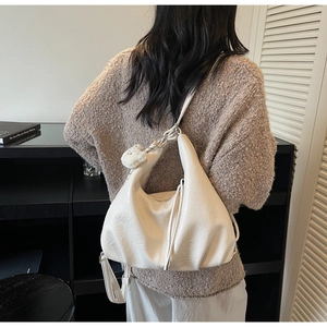 Close-up of cream hobo bag with pleated leather texture and plush bear charm