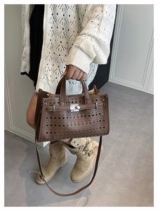 Close-up of laser-cut hollow pattern and metal twist lock on a dark brown leather tote bag