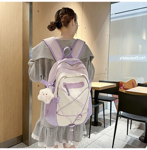 Detail of lavender nylon backpack with bungee cord and cloud charm on a model