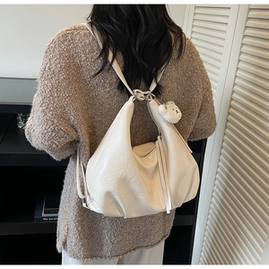 Detail of cream hobo bag with adjustable strap and cute plush bear charm on side