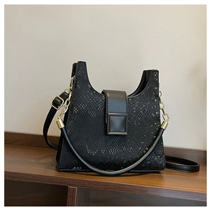 Detailed macro view of black faux snakeskin texture and metal chain handle on bag