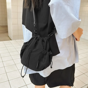Detail of black nylon bucket bag featuring drawstring closure and mesh side pocket