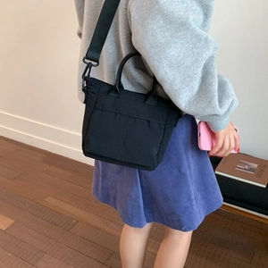 Side view of woman carrying a black nylon crossbody bag with adjustable strap for daily use