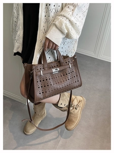 Detail of laser-cut perforated dark brown leather tote with a stylish metal twist lock