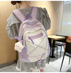 Detailed back view of a purple and beige patchwork school backpack with a plush star charm