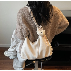 Detailed back view of off-white hobo bag featuring natural pleats and long tassels
