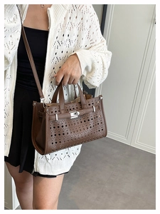 Detail of brown hollow-out tote bag with laser-cut holes and metal lock closure