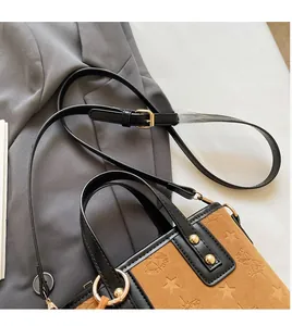 Detail of caramel suede bucket bag with star embossing and adjustable gold buckle strap