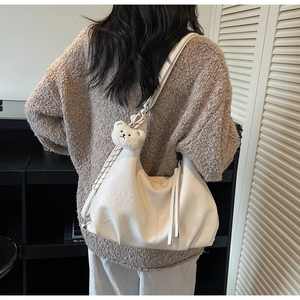 Macro view of creamy white faux leather tote bag with soft pleated texture and bear charm