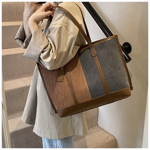 Détail d'un grand sac cabas bicolore avec toile texturée et garnitures en cuir marron