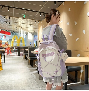 Detail view of purple and white nylon backpack with elastic cord and plush pendant accessory