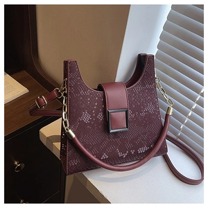 Close-up of snakeskin-textured burgundy handbag with square metal buckle and chain strap