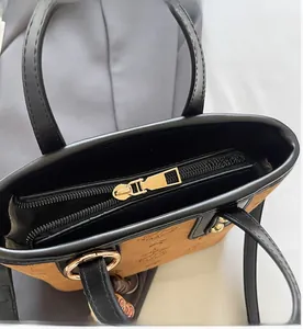 Detailed top view of the bag showing smooth gold zipper closure and logo embossed leather